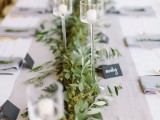 a eucalyptus table runner with delicate glass candle holders and chalkboard tags