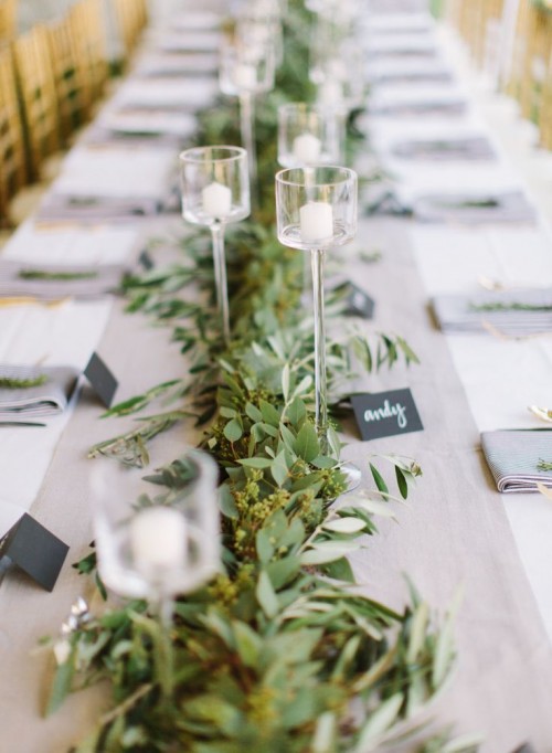 a eucalyptus table runner with delicate glass candle holders and chalkboard tags