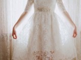 a vintage-inspired white lace A-line knee dress with an illusion neckline, long sleeves and an embellished sash