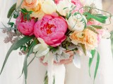 a lovely Valentine wedding bouquet of white, yellow and bold pink blooms and greenery and long white ribbons is beautiful and tender
