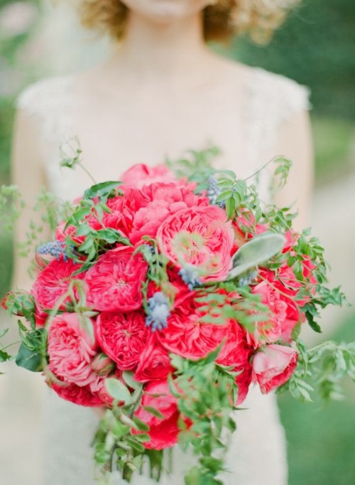 a luxurious wedding bouquet of pink peony roses, lots of greenery and some berries feels and looks like Valentine's Day