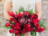 a gorgeous red and burgundy blooms and ferns and greenery is a beautiful statement with color for a Valentine bride
