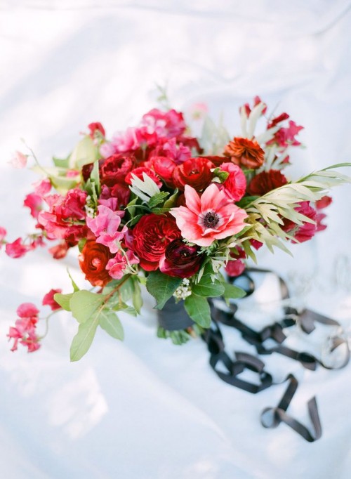 a pink, red, burgundy wedding bouquet with greenery is a bold and chic statement for a Valentine bride
