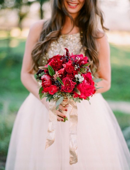 a super bold red and deep purple wedding bouquet with various berries, greenery and a gold glitter ribbon is romantic and stylish