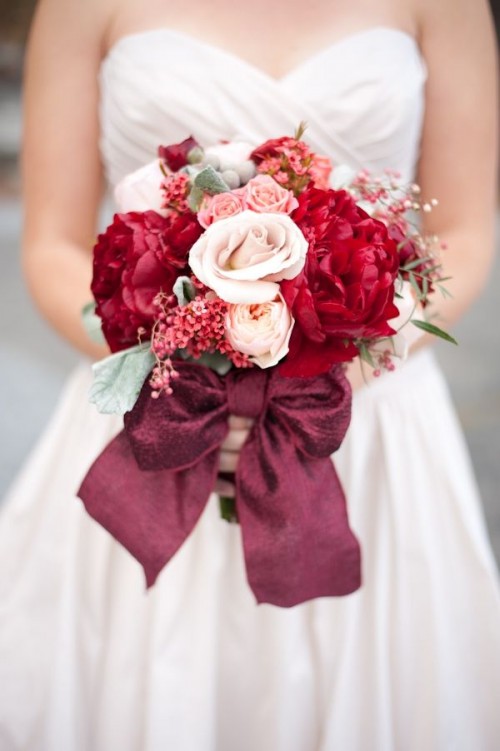 a bright wedding bouquet of blush, red, orange blooms, berries, cotton and a lovely burgundy ribbon bow is amazing for a Valentine wedding