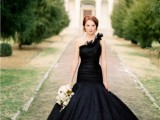 a black mermaid one shoulder wedding dress with a draped bodice, ruffles on the shoulder and a full skirt for a sophisticated wedding