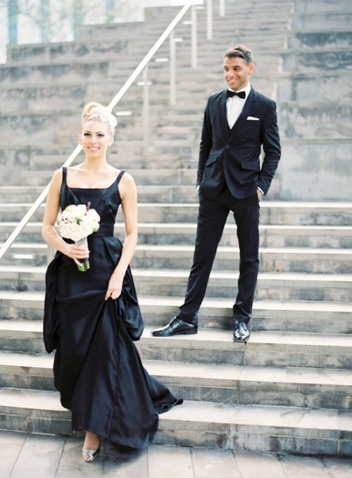 a black A-line wedding dress with thick straps and a square neckline plus a pleated skirt and a white wedding bouquet for a chic modern wedding
