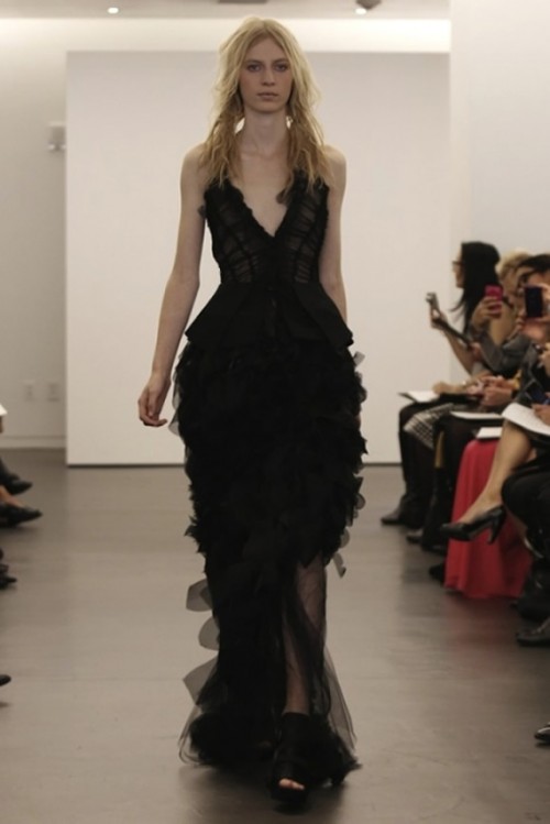 a fitting black wedding dress with a ruffle skirt, a deep neckline and no sleeves and a train for a modern Halloween wedding
