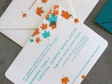a colorful fall wedding invitation suite done with orange and aqua colored leaves