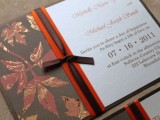 a dark fall wedidng invitation suite in chocolate brown, burgundy and orange with a ribbon and a bow