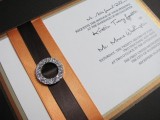 an elegant wedding invitation with orange and brown stripes and an embellished buckle