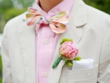 a fresh and bright take on a summer groom’s look with an off-white suit, a pink shirt, a colorful bow tie and a floral boutonniere