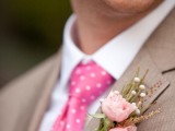a light brown suit with a pink polka dot tie, a floral boutonniere and a white shirt