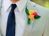 a fresh summer wedding outfit with a grey thin stripe suit, a navy tie and a colorful boutonniere