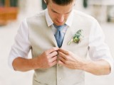 a simple neutral groom’s outfit with a tan waistcoat, a blue tie and a white shirt