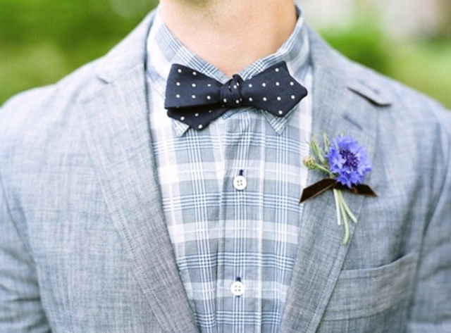 A grey suit, a plaid grey shirt, a navy polka dot bow tie and a bold floral boutonniere
