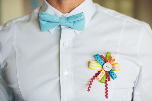a white shirt, no jacket, a blue bow tie, a colorful boutonniere for a cheerful touch to your summer look