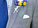 a grey suit, a plaid blue shirt, a bold blue tie and a colorful floral boutonniere for summer