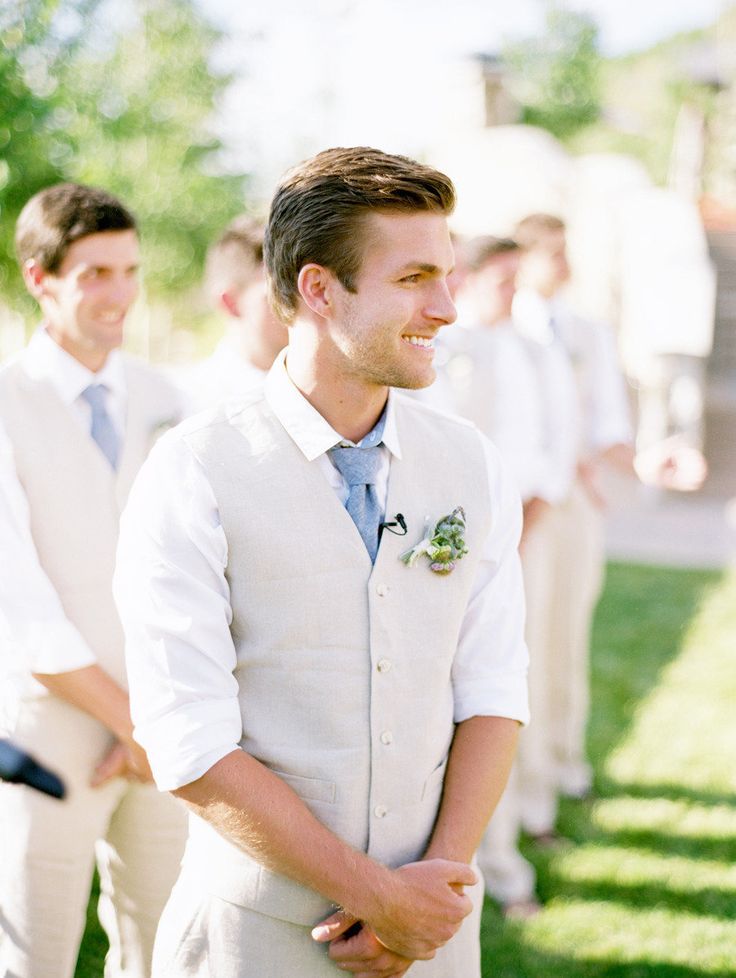 A neutral and comfortable groom's look with a white shirt, a blue tie, a tan vest and pants