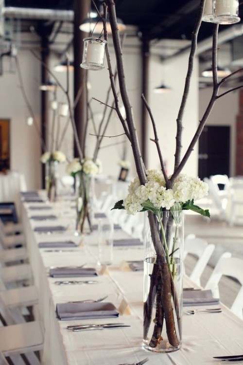 chic minimalist wedding centerpieces of branches and white hydrangeas plus candle lanterns
