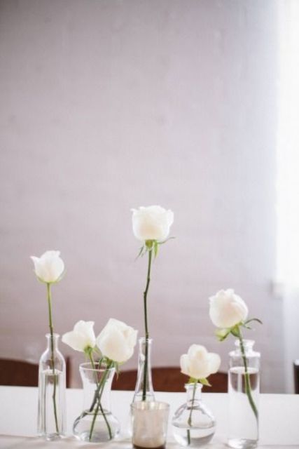 a minimalist wedding centerpiece of white roses in bottles is a chic and timeless idea to go for