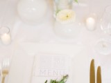 a minimalist wedding tablescape with a greenery twig, white bloom centerpieces and candles