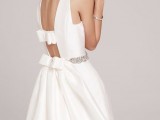 a minimalist white plain wedding dress with an A-line silhouette, a cutout back with bows and an embellished sash