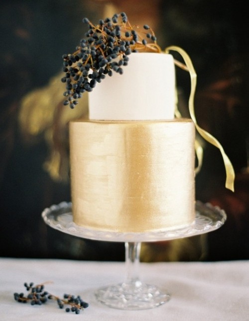 a stylish minimalist wedding cake with a white and gold tier and some berries on top