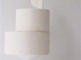 a minimalist white wedding cake with creative asymmetry and a sugar white petal on top for a refined touch