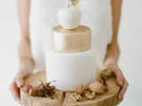 a minimalist fall wedding cake in gold and white and with a sugar white apple on top