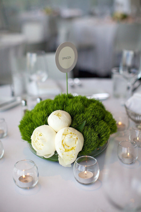 a minimalist wedding centerpiece of moss and white blooms plus candles in bubble candle holders around