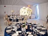 a refined navy and white tablescape with a navy tablecloth, a lush white floral centerpiece and some elegant cutlery