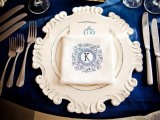 a chic place setting with a navy tablecloth, a refined placemat, printed napkins and silver