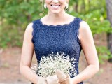 a navy lace sheath bridesmaid dress and a baby’s breath bouquet plus rhinestone earrings