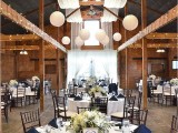 chic navy and white table settings with white tablecloths, navy napkins, white floral centerpieces, lights and paper lamps over the space