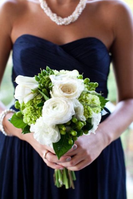 a strapless navy draped bridesmaid dress, a pearl necklace and a white rose bouquet for a chic look
