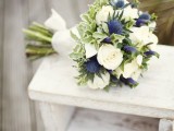 a wedding bouquet with white roses and blue thistles is a cool idea for a bride or for bridesmaids