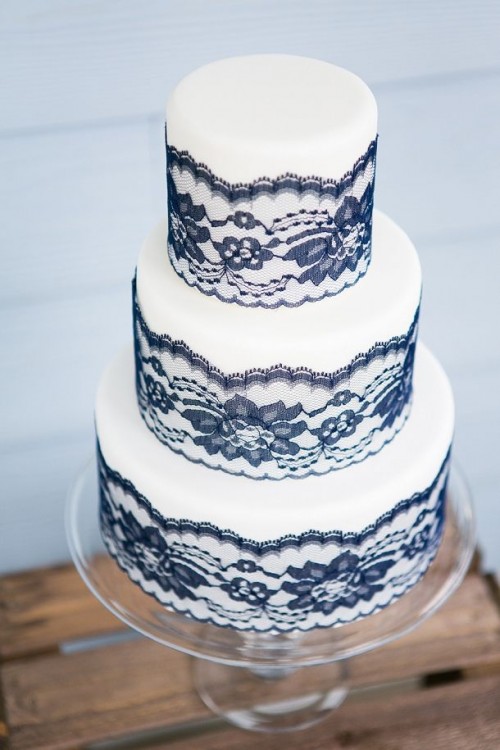 a refined wedding cake in white decorated with navy lace is a great idea to continue your wedding color scheme