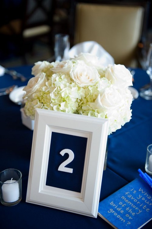 a navy tablecloth, a navy and white table number, a white floral centerpiece for creating a bold and contrasting tablescape