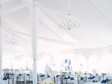 a chic navy and white tablescape with a white tablecloth, navy napkins, neutral blooms and refined crystal chandeliers