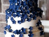 a white wedding cake with navy sugar flowers is a fantastic dessert that will keep your wedding color scheme up