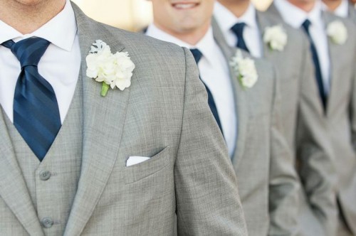 groomsmen wearing three-piece grey suits with white shirts and boutonnieres and navy ties