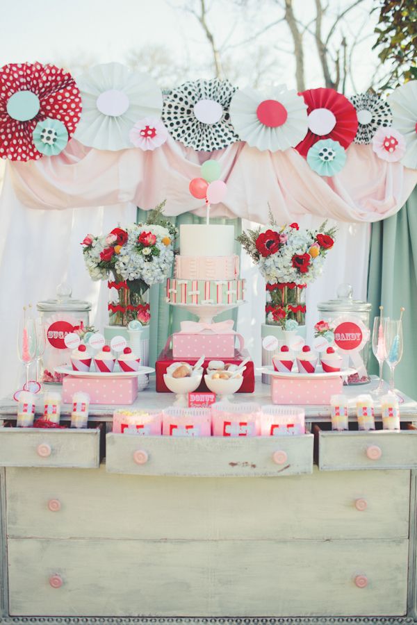 A sweet retro wedding dessert table with red, mint and grey paper fans, bright bloom arrangements, colorful popcorn paper bags
