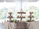 a rustic dessert table with wood slice stands for sweets, a barrel with sweets and some potted greenery