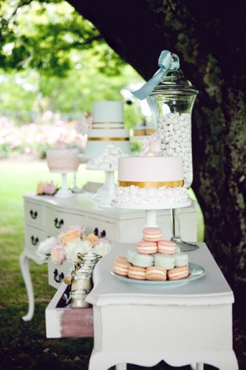 an elegant vintage dessert table composed of two white sideboards and simple white stands for sweets