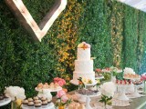a rustic table with a doliy runner, a green living wall as a backdrop and a marquee heart on the wall