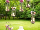 a chic garden wedding dessert table with hanging candle lanterns with pink blooms, pink lemonade, flowers and sweets