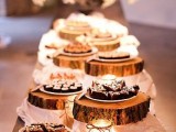 a rustic dessert table with candles and wood slice stands plus pendant lamps to accent the table a lot
