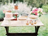 a bright summer dessert table with colorful blooms and greenery, tasty and delicious sweets and petals