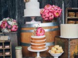 a rustic wedding dessert table organized on wooden crates and barrels, with bright blooms and white porcelain for sweets